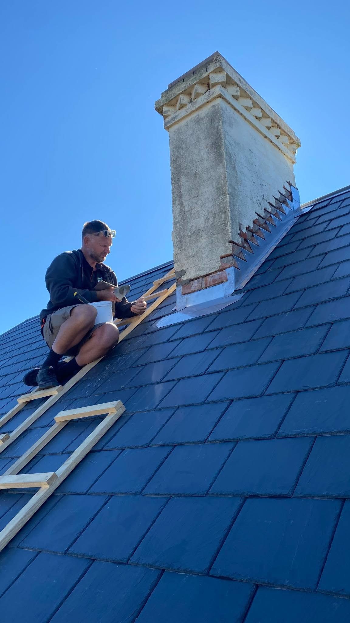 R.A. Moore working on slate roof chimney